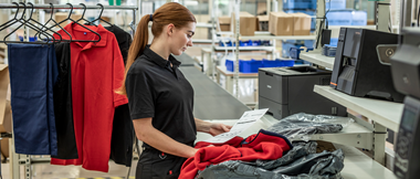 A retail employee reading a return slip and preparing a customer return in a warehouse office
