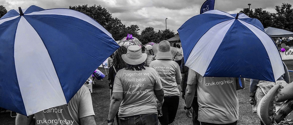 Deze scène, die in zwart-wit is gefilmd maar met blauwe accenten, toont een Relay for Life liefdadigheidstocht op een renbaan terwijl tientallen mensen helpen geld in te zamelen voor het goede doel. 