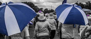 Deze scène, die in zwart-wit is gefilmd maar met blauwe accenten, toont een Relay for Life liefdadigheidstocht op een renbaan terwijl tientallen mensen helpen geld in te zamelen voor het goede doel. 