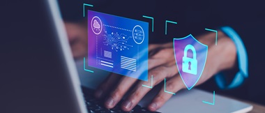 Mains tapant sur un ordinateur portable avec une icône de sécurité superposée dessus