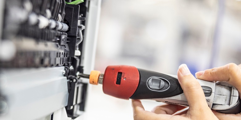 Woman's hands holding a tool fixing the inside of an open printer